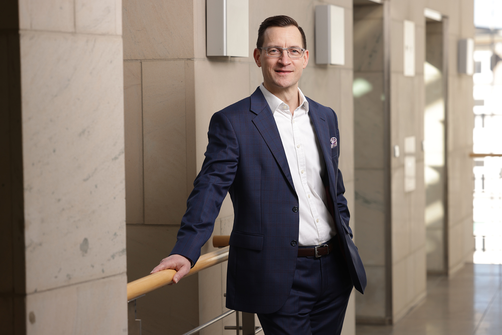 Portrait von Prof. Dr. Mike Schneider steht an ein Geländer gelehnt