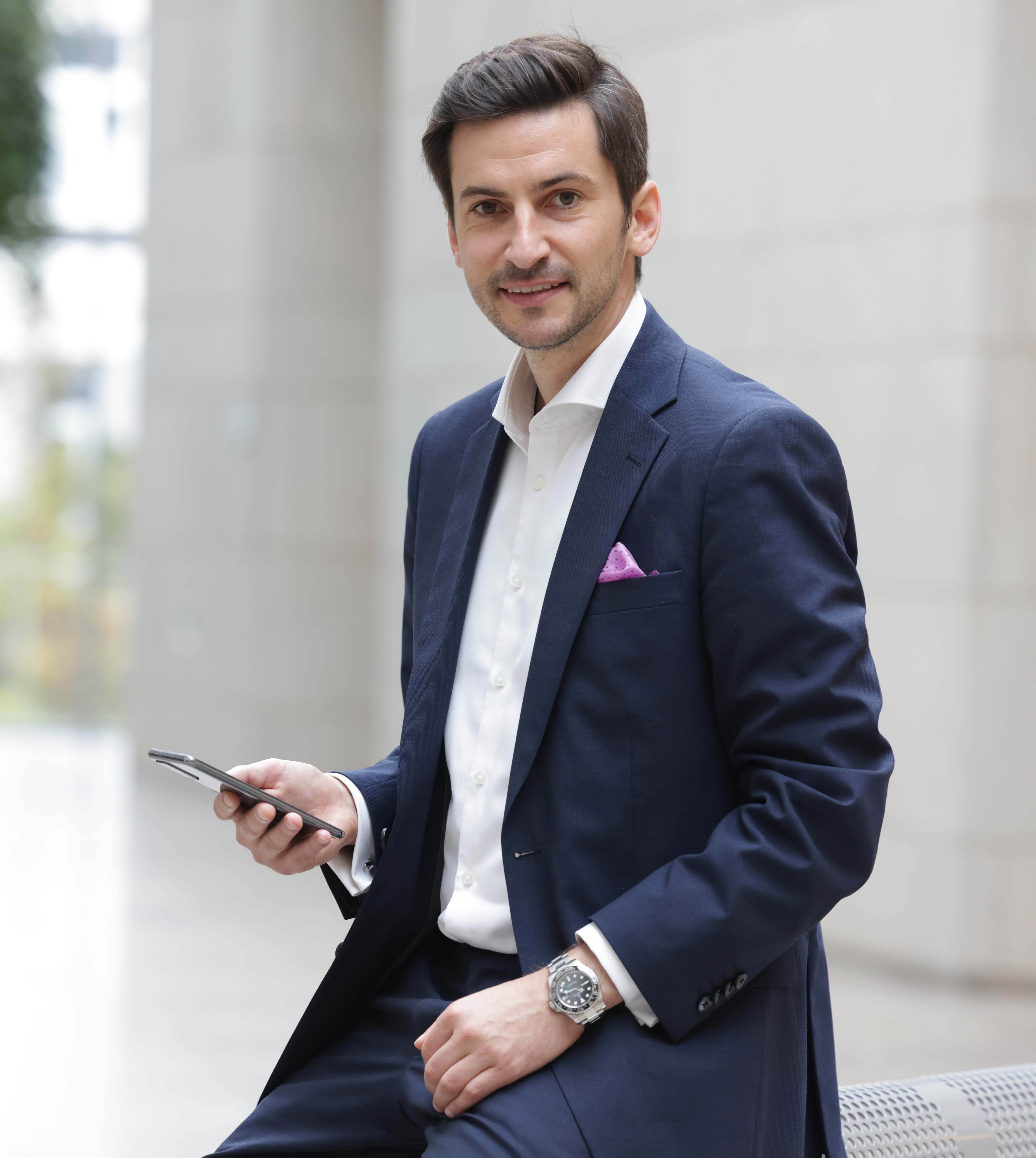 Prof. Julius Beck schaut von seinem Handy hoch in die Kamera