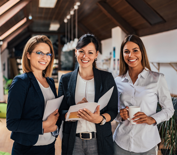 Drei Business Frauen mit Unterlagen schauend lächelnd in die Kamera