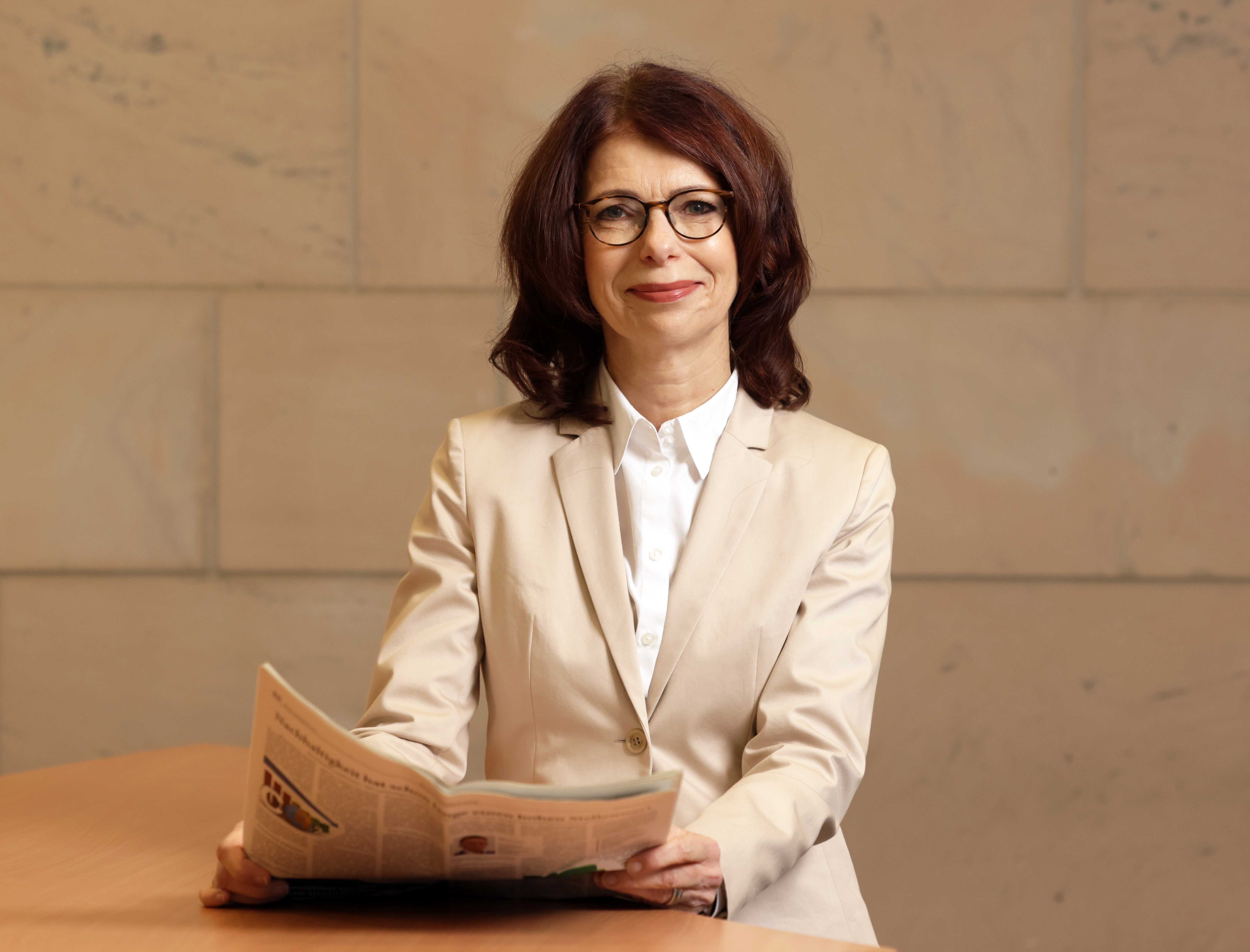 Prof. Anne Böhm-Dries schaut von einer Zeitung auf in die Kamera