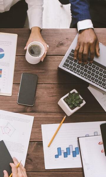 Tisch mit Laptops, Smartphones, Notizen und Diagrammen zur Analyse digitaler Lehrformate.
