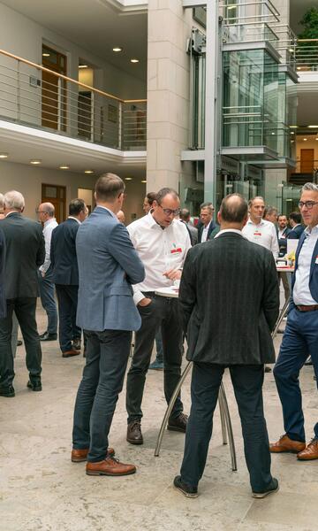 Teilnehmende vom Forum Firmenkundengeschäft unterhalten sich in kleinen Gruppen im Foyer