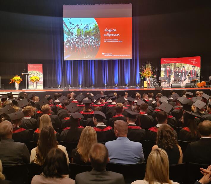 Absolventen und Publikum schauen nach vorne auf die Bühne