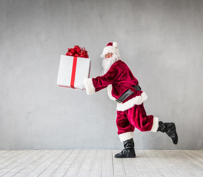 Der Weihnachtsmann trägt ein großes Geschenk