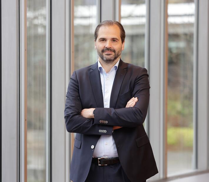 Prof. Martin Scheffel lehnt an Glaswand