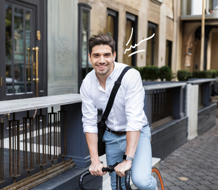 Junger Mann auf einem Fahrrad blickt lachend in die Kamera