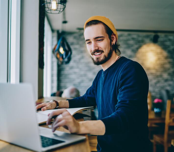 junger Mann arbeitet in einem Cafe an einem Laptop