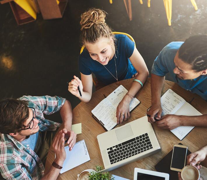 Studierende sitzen gemeinsam am Tisch und unterhalten sich