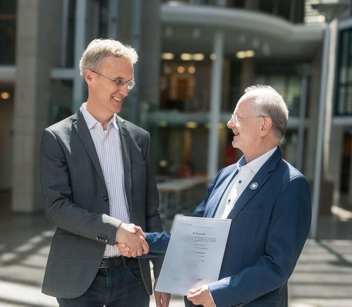 Zwei lächelende Männer schütteln sich die Hände