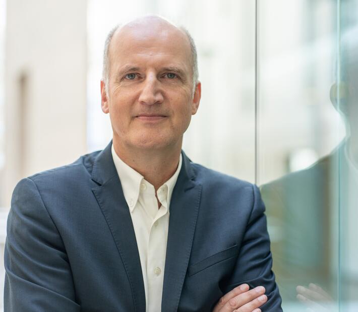 Ein Mann im Anzug steht an einer Glaswand