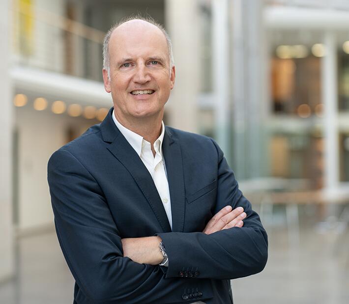 Ein Mann im Anzug steht im Foyer der Hocschule