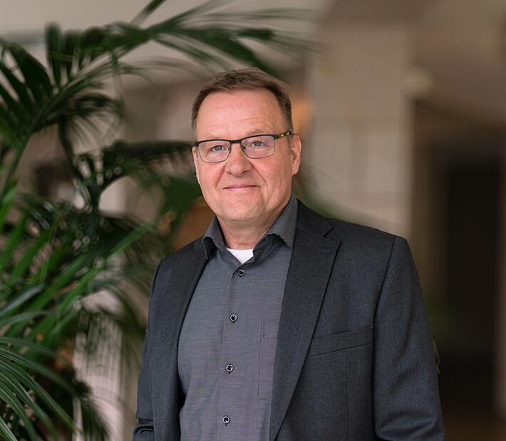 Ein Mann im Anzug lächelt in die Kamera