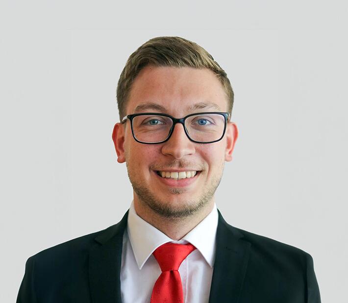 Ein junger Mann mit Brille lächelt