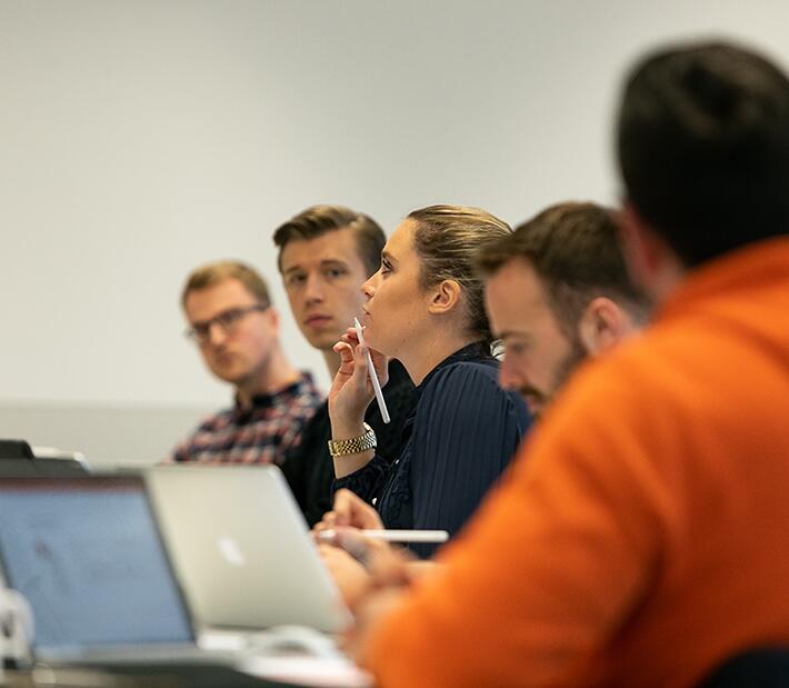 Eine Gruppe Menschen sitzt am Tisch mit Laptop und Unterlagen