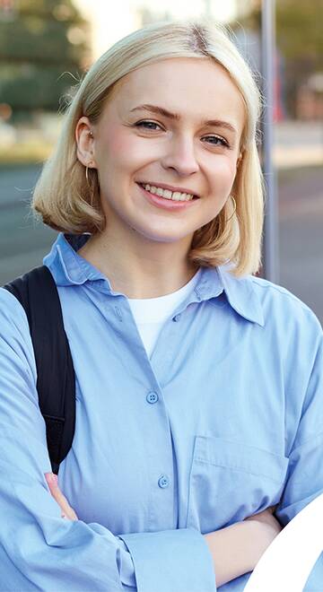 junge blonde Frau steht vor einem Gebäude