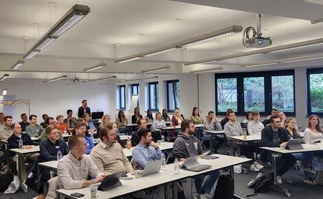 Master-Studierende sitzen an Tischen