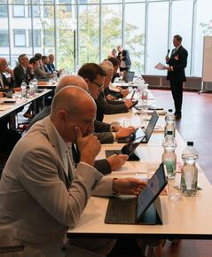 Teilnehmende vom Forum Firmenkundengeschäft sitzen in der Aula an Tischen