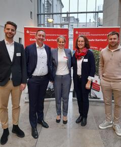 Zwei Fraeun und drei Männer stehen in einer Gruppe