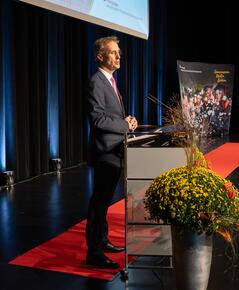 Der Rektor der Hochschule steht auf der Bühne am Rednerpult