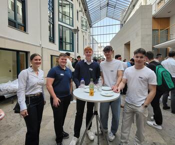 Eine Gruppe junger Menschen steht an einem Stehtisch