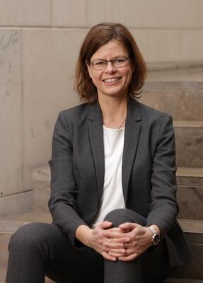 Prof. Anja Schulz sitzt auf einer Treppe un dlächelt in die Kamera