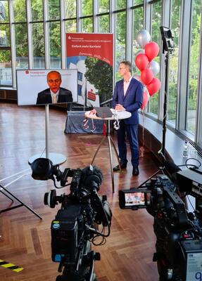 Kameras sind auf Rektor Bernd Heitzer gerichtet, der sich hinter einem Stehtisch befindet