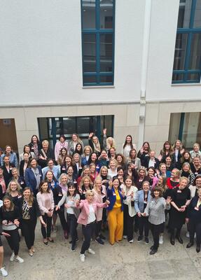 Eine Gruppe vieler Frauen steht im Foyer und schaut in die Kamera