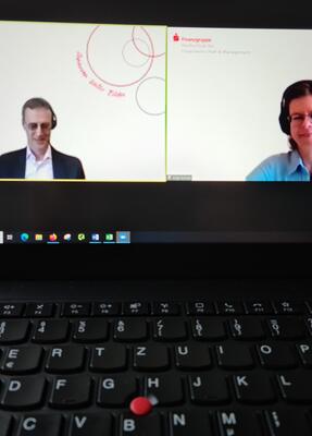 Foto von einem Laptopmonitor, der ein Zoom-Meeting mit Bernd Heitzer und Anja Schulz zeigt
