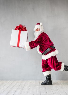 Der Weihnachtsmann trägt ein großes Geschenk