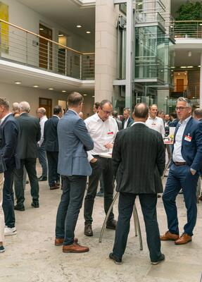 Teilnehmende vom Forum Firmenkundengeschäft unterhalten sich in kleinen Gruppen im Foyer
