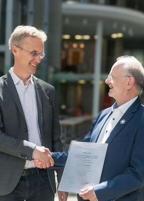 Zwei lächelende Männer schütteln sich die Hände