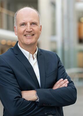 Ein Mann im Anzug steht im Foyer der Hocschule