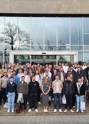 Eine grosse Gruppe junger Menschen steht vor dem Gebäude der HFM