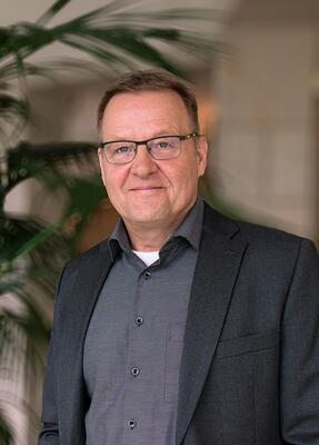 Ein Mann im Anzug lächelt in die Kamera