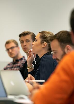 Eine Gruppe Menschen sitzt am Tisch mit Laptop und Unterlagen