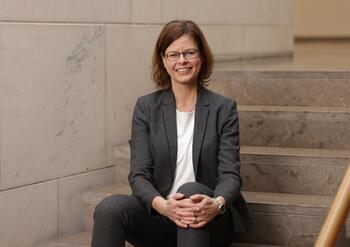 Prof. Anja Schulz sitzt auf einer Treppe un dlächelt in die Kamera