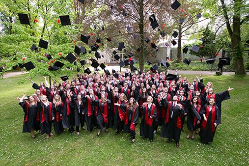Gruppe von Absolventen die Hüte werfen bei der Graduierungsfeier