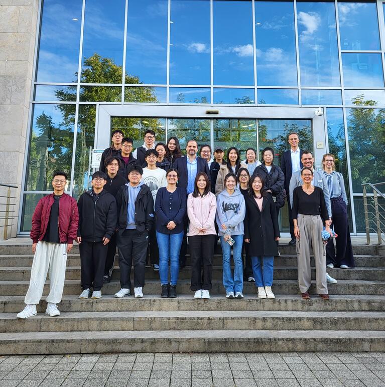 Gruppe von chinesischen Studierenden steht vor Portal der HFM.