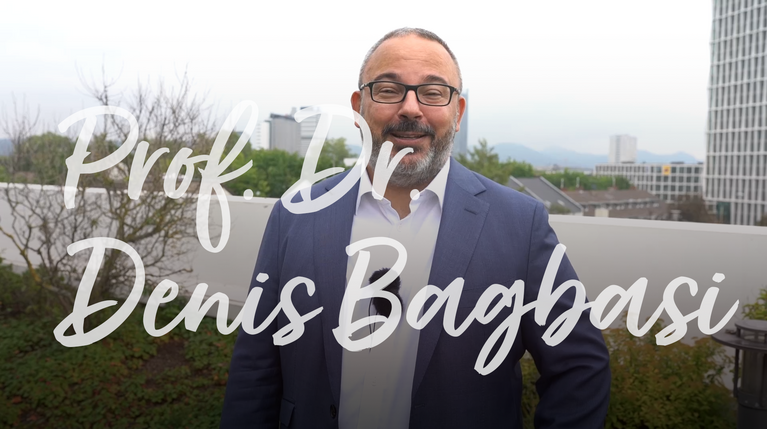 Professor Dr. Denis Bagbasi steht im Freien vor einer urbanen Hintergrundkulisse.