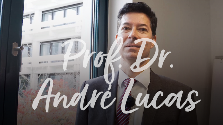 Prof. Dr. André Lucas steht vor einem Fenster und spricht über seine fachlichen Schwerpunkte.