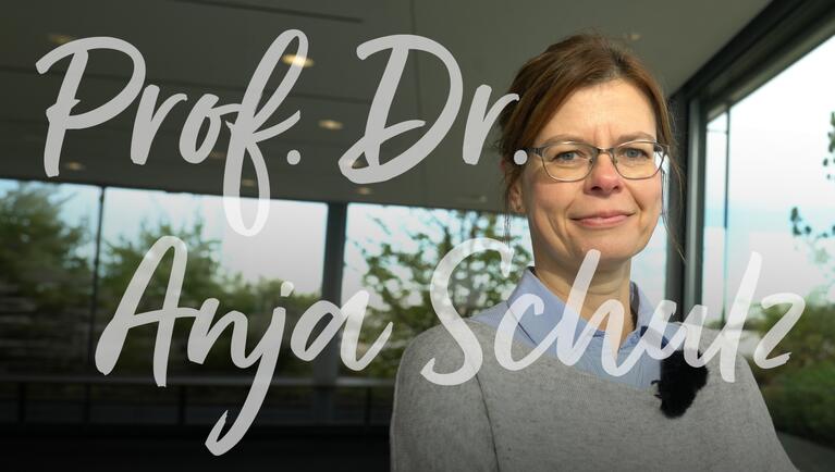 Prof. Dr. Anja Schulz steht in einem modernen Raum mit großen Fenstern und Blick ins Freie.